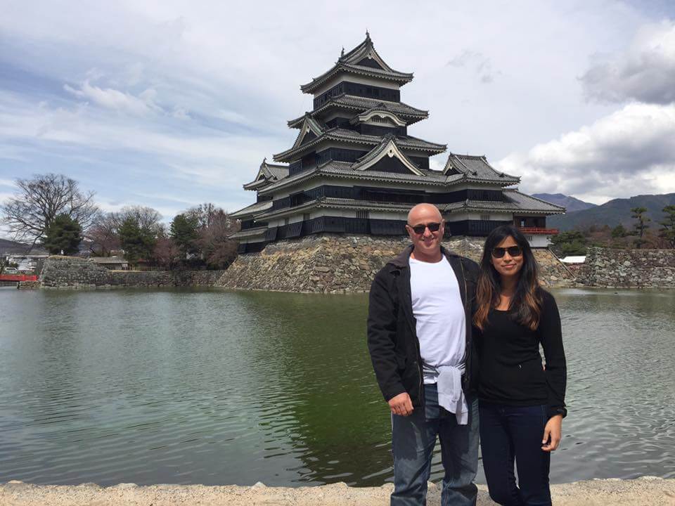Couple standing in front of a river with temple in the background