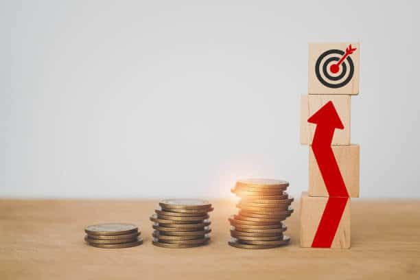 For financial concepts , financial investment business stock growth, profit, business strategy, business target. Red up arrow with dartboard on wooden cube block and stacks of coins