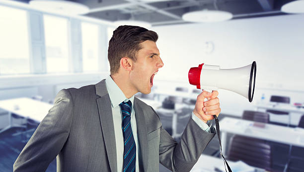 Businessman shouting in loudspeaker against classroom